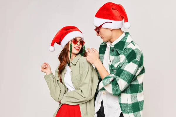 Чоловік і жінка в сонцезахисних окулярах Санта-капелюхи мода обіймає сірий фон — стокове фото