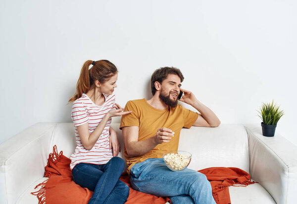 Man and woman watching movies indoors with popcorn and flower in a pot