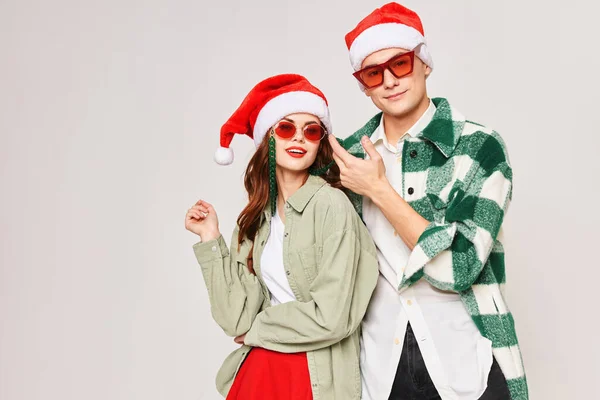 Bonito homem mulher vestindo óculos de sol vestindo Papai Noel chapéus Natal inverno abraços — Fotografia de Stock