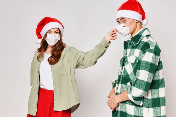 Чоловік і жінка в різдвяних капелюхах медичні маски захист свято весело — стокове фото
