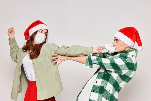 Сімейна пара в різдвяних капелюхах медичні маски емоції свято Новий рік — стокове фото