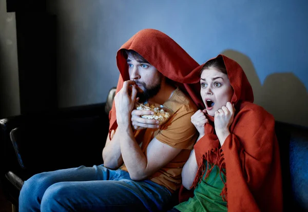 Чоловік і жінка з червоною плямою на голові сидять на дивані перед телевізором у приміщенні — стокове фото