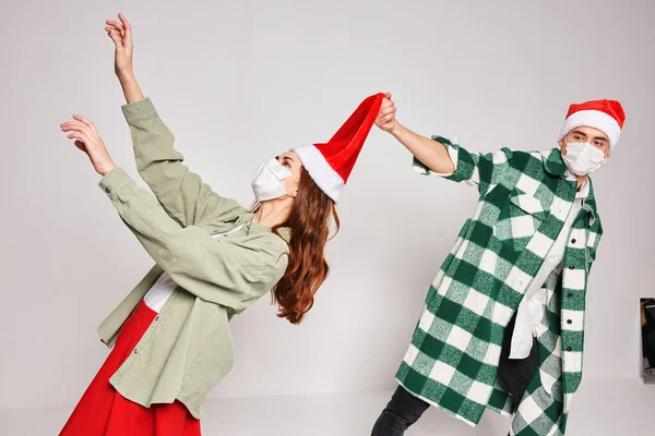 Молода пара святкує Різдво разом в емоціях капелюха Санта медичні маски на обличчі — стокове фото