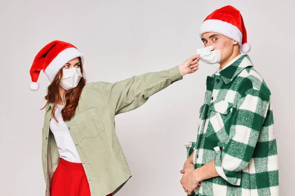 Чоловік і жінка в Новорічні капелюхи медичні маски карантинне свято Новий рік — стокове фото