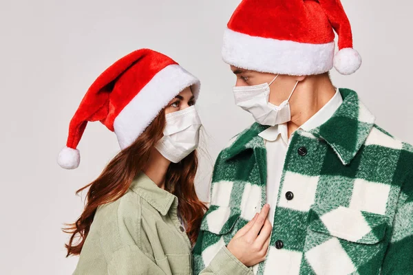 Bonito casal jovem Natal chapéus máscaras médicas close-up abraço — Fotografia de Stock