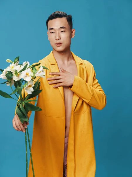 黄色のコートのセクシーな男は彼の手に白い花の花束を持っています — ストック写真