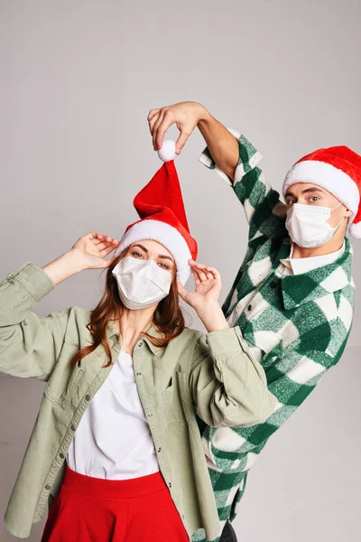 Νεαρό ζευγάρι φορώντας ιατρικές μάσκες στο πρόσωπό τους Χριστούγεννα διασκέδαση διακοπές φιλία — Φωτογραφία Αρχείου