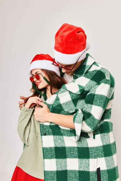 Чоловік зігріває жінку сорочкою Різдвяні капелюхи святкові забави темні окуляри — стокове фото