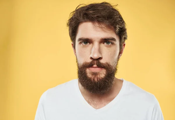 Un hombre con barba y bigote sobre un fondo amarillo y una camiseta blanca —  Fotos de Stock