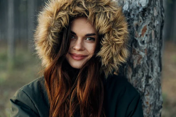 Uma mulher em um capuz está se apoiando em uma árvore na natureza da floresta legal — Fotografia de Stock