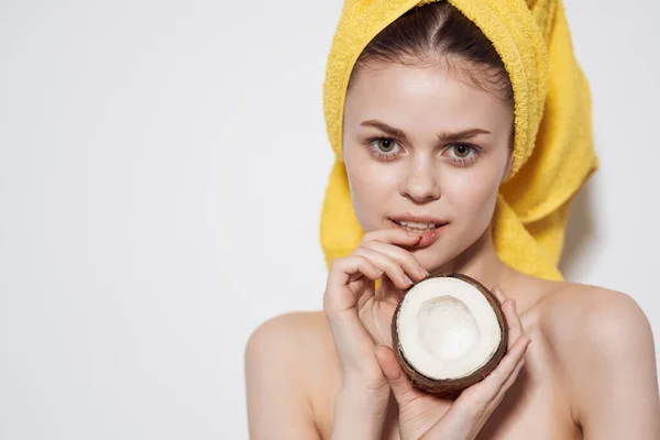 Wanita cantik dengan handuk kuning di kepalanya memegang tangan kelapa eksotis kulit bersih spa — Stok Foto