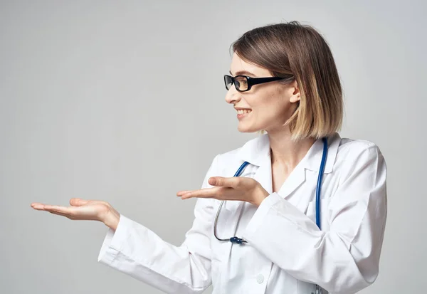 Enfermera con un vestido médico haciendo gestos con las manos sobre un fondo claro —  Fotos de Stock