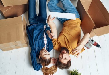 Kutuları olan kadın ve erkeğin portresi gelecekteki apartman planlarını taşıyor.
