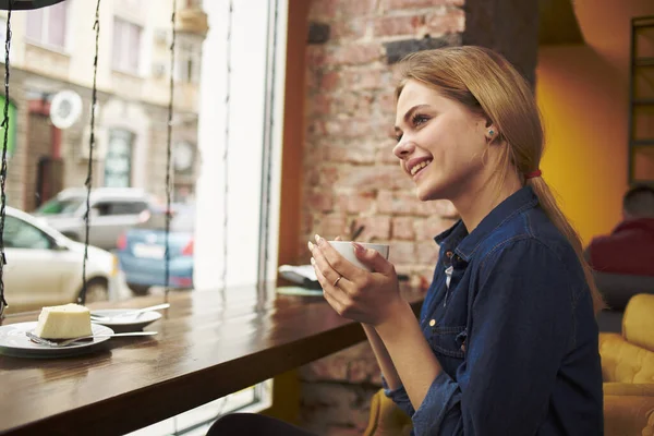 Mulher bonita sentada em uma mesa de café com uma xícara de café da manhã estilo de vida — Fotografia de Stock