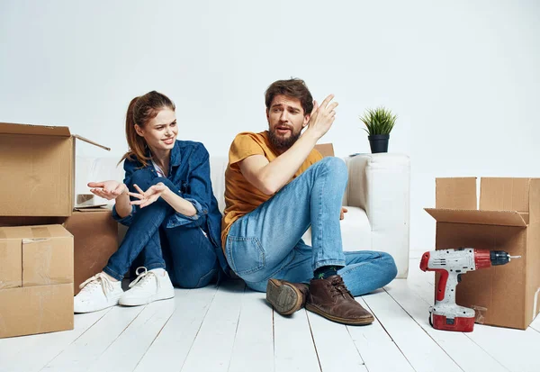 Ένας άντρας και μια γυναίκα κάθονται στο πάτωμα με ανοιχτά κουτιά και εργαλεία για επισκευή. — Φωτογραφία Αρχείου