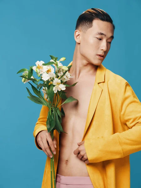 青い背景に花の花束を持つ黄色のジャケットの半裸の男 — ストック写真