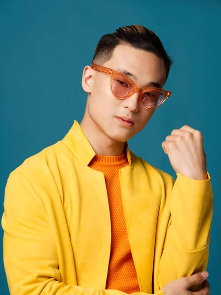 Μοντέρνος τύπος με πορτοκαλί γυαλιά σε μπλε φόντο και κίτρινο μπουφάν — Φωτογραφία Αρχείου