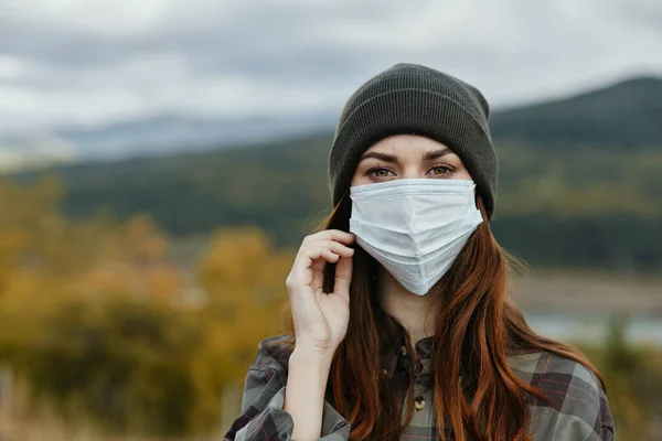 Ładna kobieta z maską medyczną na twarzy i kapeluszu natura jesienny las — Zdjęcie stockowe