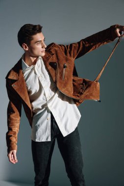 Kahverengi ceketli yakışıklı adam gri arkaplan kopyalama alanına bakıyor