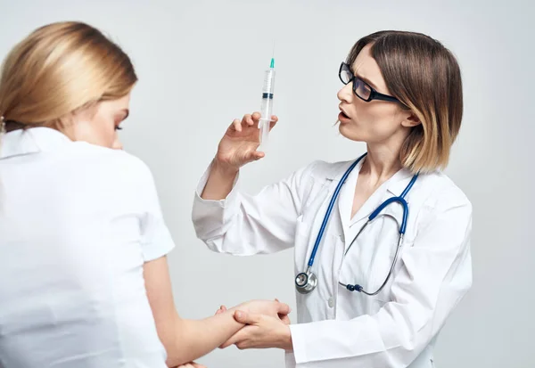 Une femme tient une seringue dans sa main et une patiente dans un t-shirt blanc est modèle effrayé — Photo
