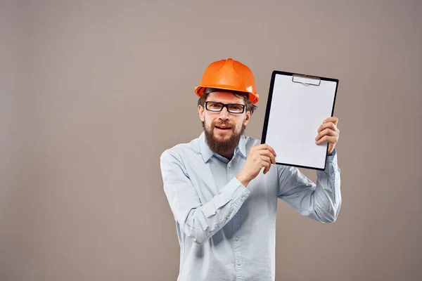 Un hombre con una camisa con un sombrero naranja ingeniero documentos de trabajo prestación de servicios — Foto de Stock