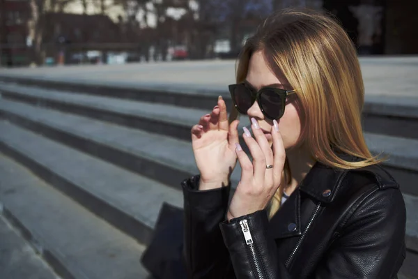 Una mujer baja por las escaleras en la calle con una chaqueta de cuero y gafas de sol — Foto de Stock