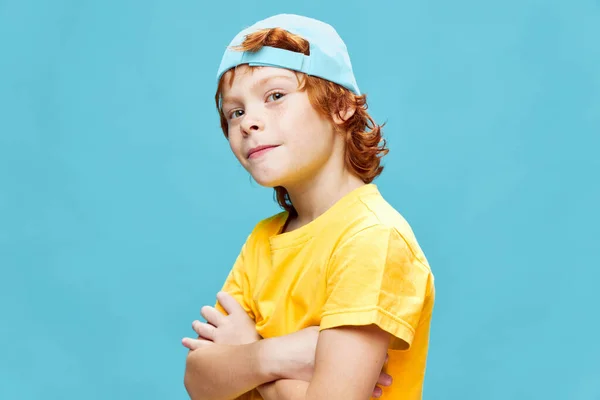 Rotschopf Junge mit blauer Mütze verschränkte Arme gelbes T-Shirt Mode — Stockfoto