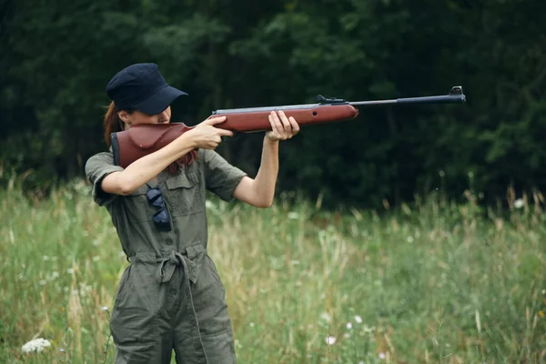 大自然中的女人手里拿着枪瞄准着一件绿色的套头衫武器 — 图库照片