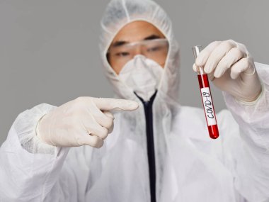 Erkek bir laboratuvar asistanı covid-19 testini işaret ediyor.