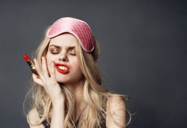 Elinde ruj, yüzünde pembe maske olan sarhoş bir kadın.