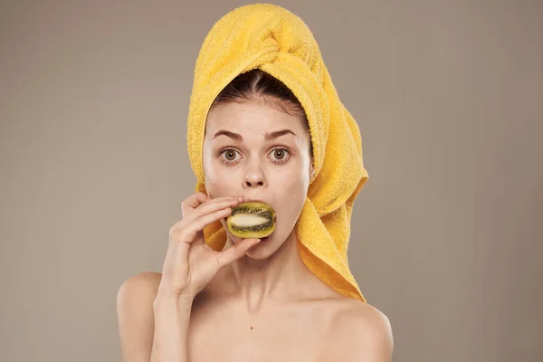 Wanita sehat di sana dengan handuk di kepalanya bersih buah kiwi vitamin latar belakang berwarna krem — Stok Foto