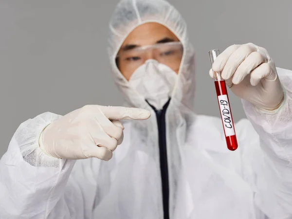A male laboratory assistant points a finger at the covid-19 tests — Stock Photo, Image