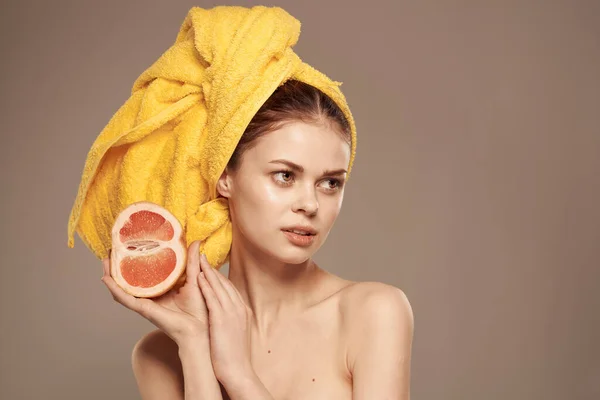 Mulher com ombros nus toalha amarela na cabeça toranja em mãos cuidados com a pele limpa — Fotografia de Stock