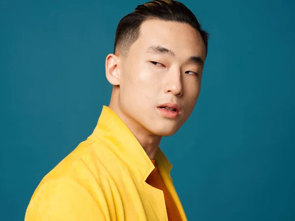 Man with narrow eyes in a yellow t-shirt on a blue background portrait cropped view — Stock Photo, Image