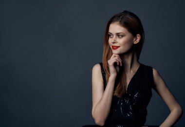 Kırmızı saçlı, gece makyajlı, siyah elbiseli hoş bayan. Arka planı gri.