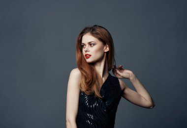 Gri arka planda elbisesi olan kızıl saçlı kadın elleriyle mekanı kopyaladı.