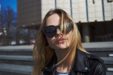 Kadın model, sonbaharda caddede binanın yanındaki merdivenlerde oturuyor.