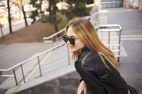 Mujer con estilo en una chaqueta de cuero y gafas en la calle en el modelo de la ciudad — Foto de Stock