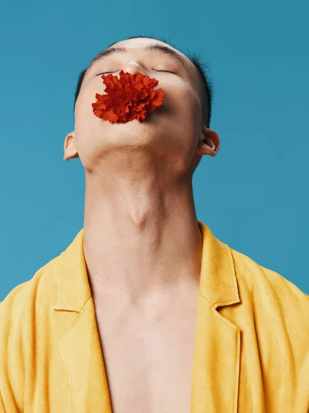 Hombre con una flor roja en la boca inclinó su cabeza hacia atrás sobre un fondo azul —  Fotos de Stock