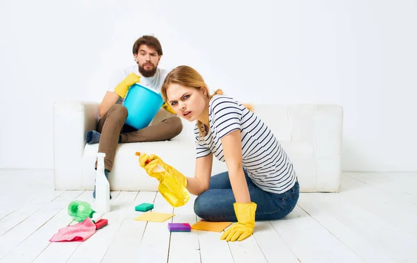 The man lies on the couch and the woman is cleaning the detergent on the floor — Stock Photo, Image