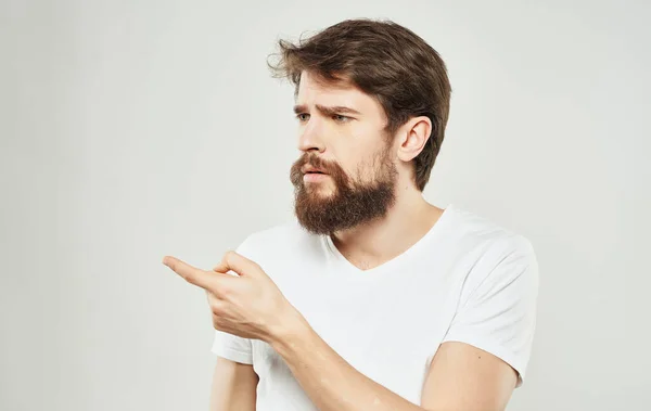Бородатий чоловік тримає голову емоції жести своїми руками біла футболка — стокове фото
