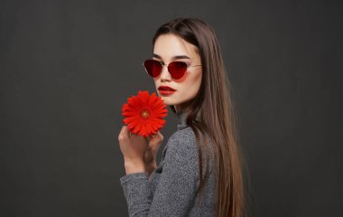 Çekici bir kadın elinde gözlük tutan kırmızı çiçek lüks kozmetik stüdyosu