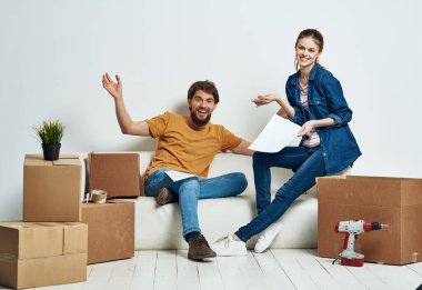 Koltuktaki kutularda eşyaları olan genç bir çift yeni eve taşınıyor.