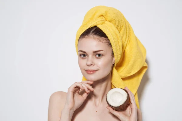 Femme dans une serviette jaune sur sa tête noix de coco dans sa main Exotiques peau propre cosmétiques naturels — Photo