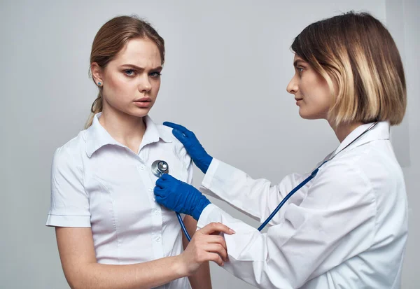 Женщина-врач со стетоскопом держит пациента за плечо на светлом фоне — стоковое фото