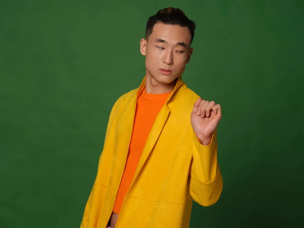 Vista recortada de un hombre con una camiseta naranja y una chaqueta amarilla sobre un fondo verde —  Fotos de Stock
