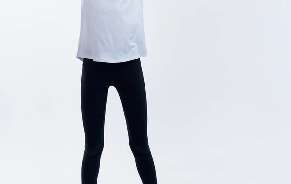 Beyaz tişörtlü atletik bir kadın ve arka planda tozluklar bacaklarını iki yana açıyor. — Stok fotoğraf