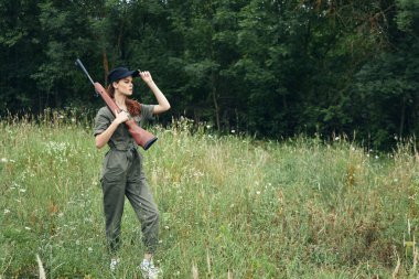 Doğada tabancalı bir kadın yeşil tulum avlıyor. 