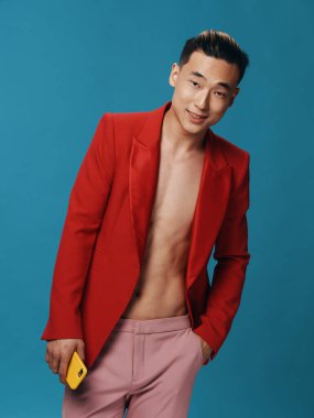 Kırmızı ceketli, elinde cep telefonu olan, pembe pantolonlu şık bir adam. 