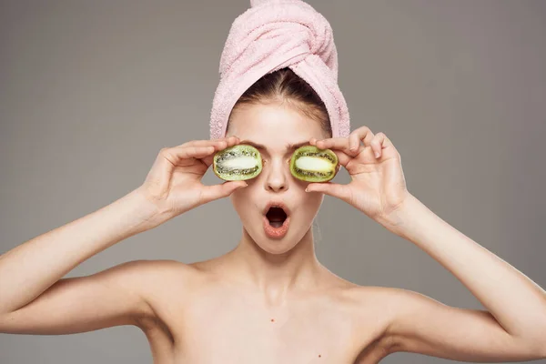 Wanita memegang mata dekat kiwi bahu telanjang latar belakang kulit abu-abu bersih — Stok Foto